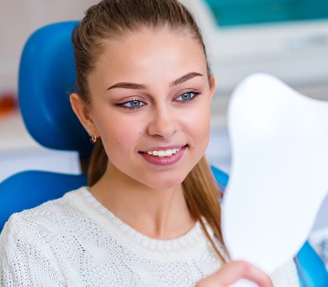 Young woman admiring her smile in a hand mirror