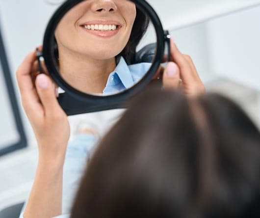 Patient's smile reflected in a hand mirror