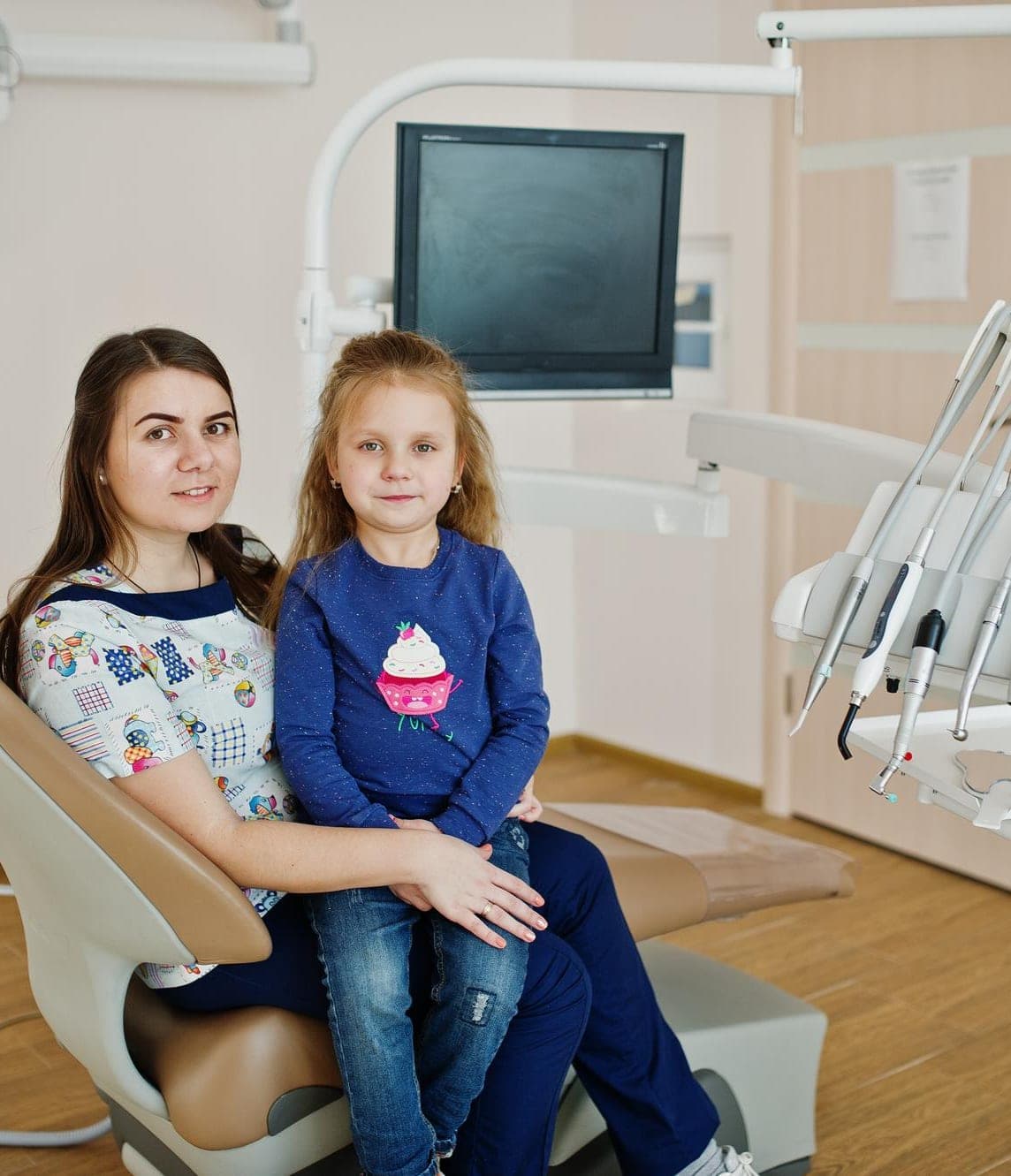 Mother and daughter smiling together in the dental chair