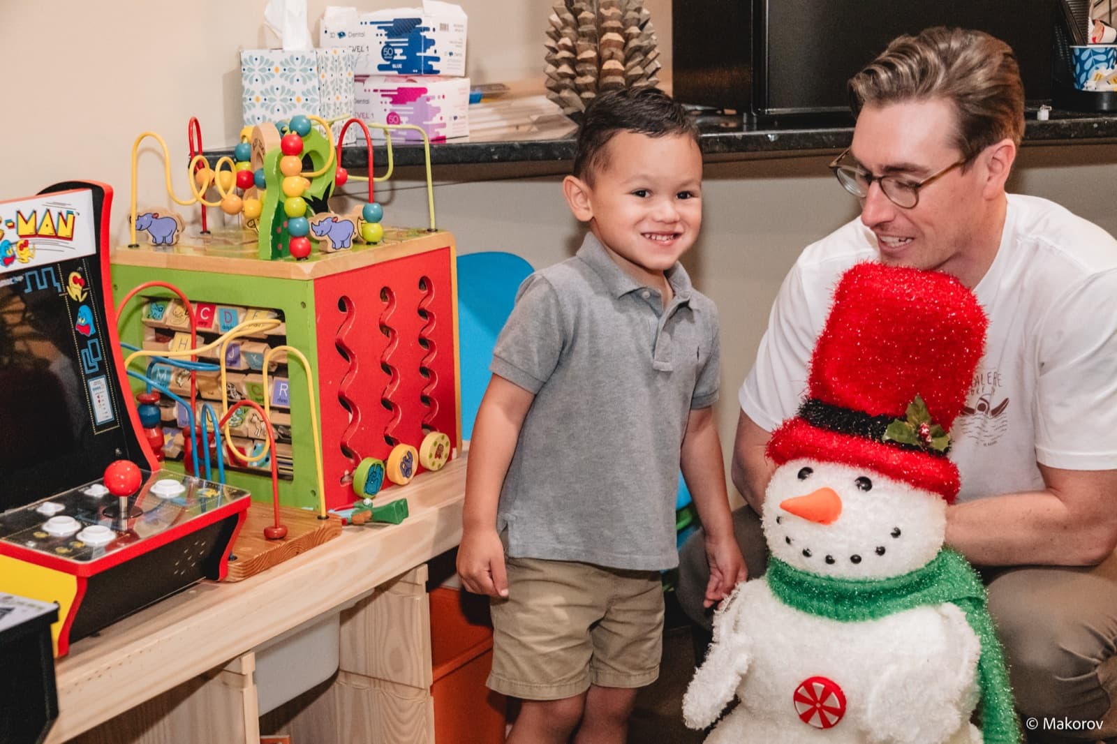 Smiling young patient and his dad with a snowman in the Landmark Smiles kids corner